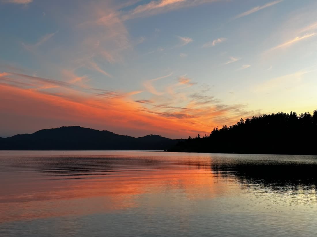 Sunset reflected across a still island lake